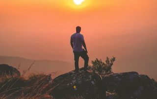 homme an randonnée dans la montagne admirant le coucher du soleil pour se reconnecter à lui-même et à la nature