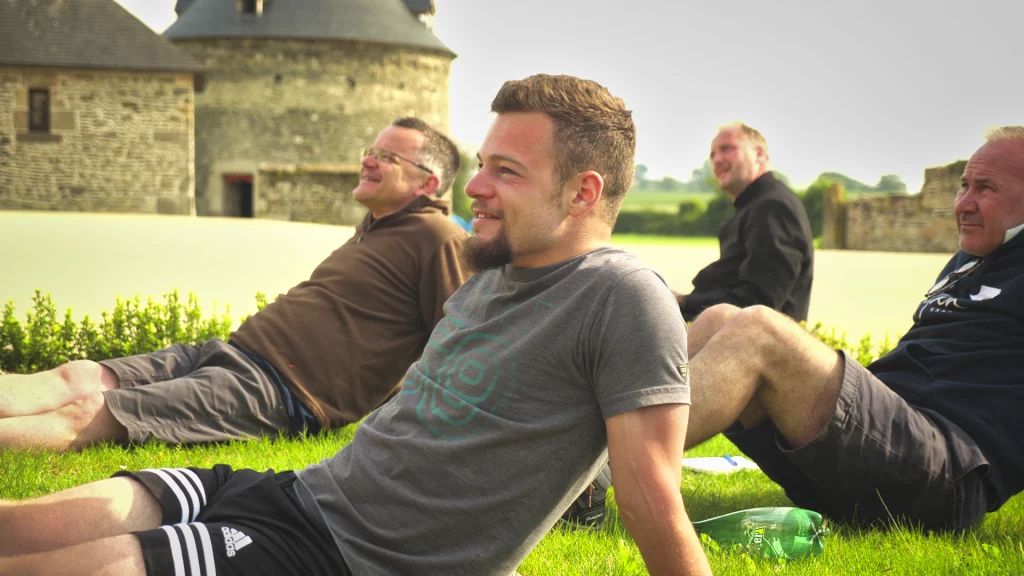 Un groupe d'homme est assis sur l'herbe pendant une rencontre de fraternité